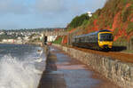 Der Wind am frühen Morgen peitscht hohe Wellen an das Festland: Lokalzug unterwegs vor schöner Kulisse nach Exeter.