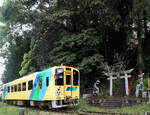 Die Heisei Chikuhô Bahn im Nordosten der Insel Kyûshû: Unmittelbar vor der Aufstiegstreppe zum Heiligtum in der Höhe oben fährt Triebwagen 406 vorbei.