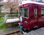 Hankyû-Konzern, Arashiyama Linie: Triebwagen 7017 wartet in Arashiyama auf den Stossverkehr mit Tausenden von Touristen, die einen friedlichen Tag am Fluss und inmitten der Kirschblüten