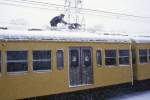 Züge des Seibu-Konzerns im heftigen Schneefall: Nach dem totalen Stromausfall versucht ein Seibu-Schaffner, den gesenkten Pantographen des Zuges 765 zu enteisen.
